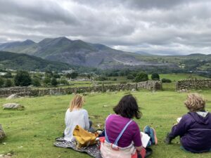 Individuals writing in the countryside. The mountain, Moel Faban, is in the background.