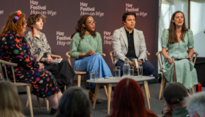 A group of people sitting on chairs in front of an audience at the Hay Festival